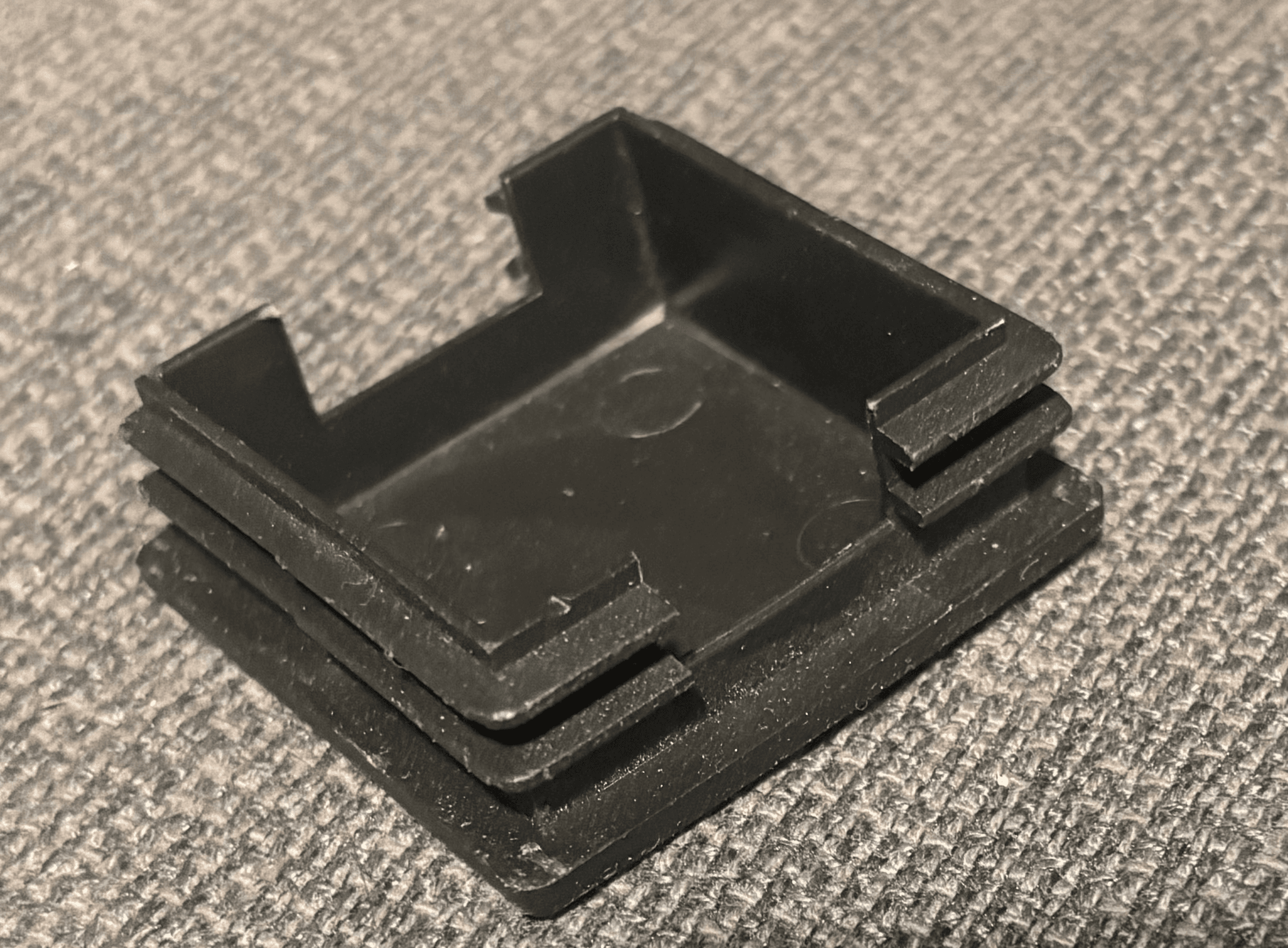 My original black weight-rack cap photographed from the hollow side, showing the walls, ribs, and two cutouts.