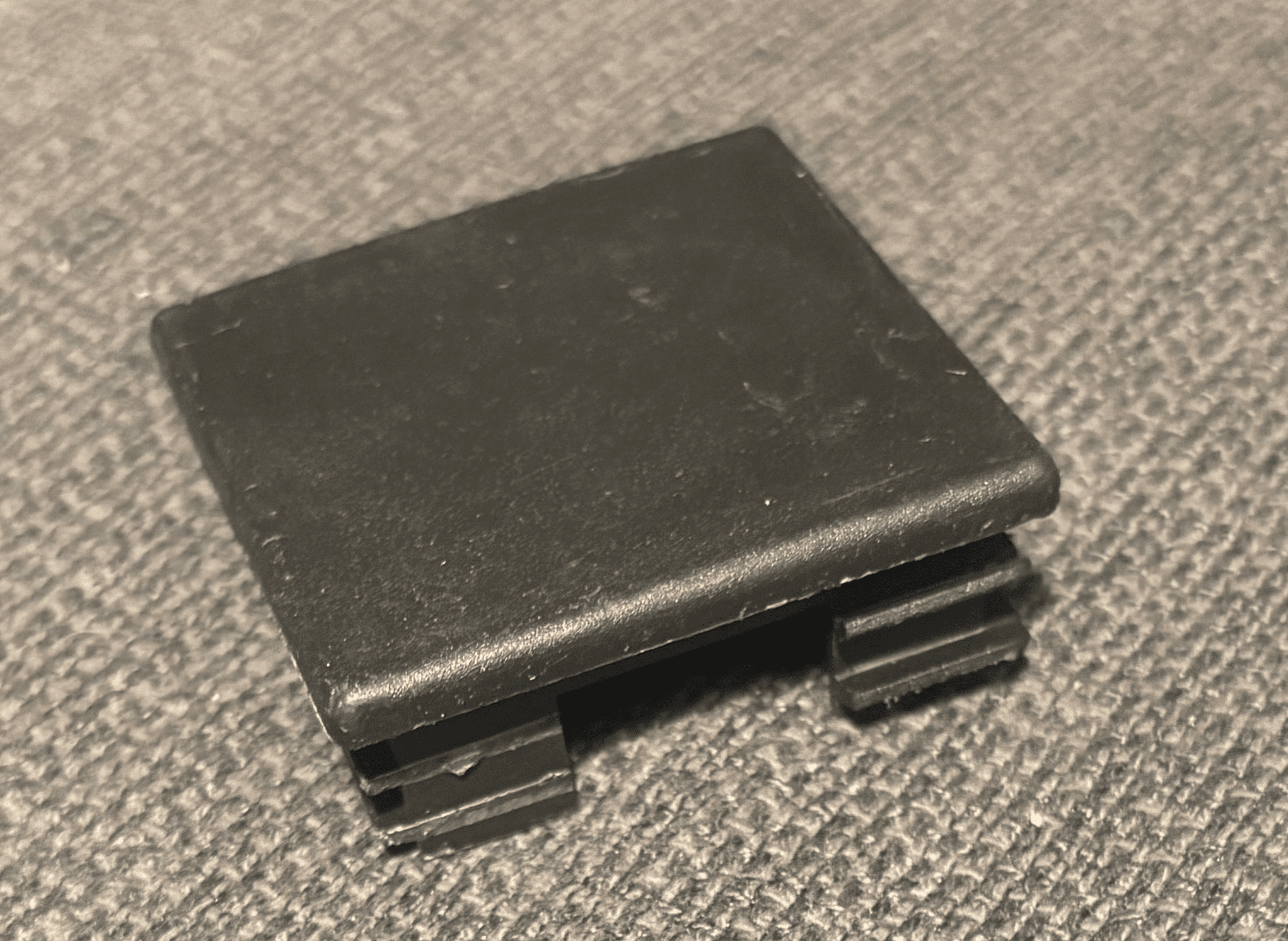 My original black weight-rack cap photographed from above, showing the square top, rounded edge, and retaining ribs.